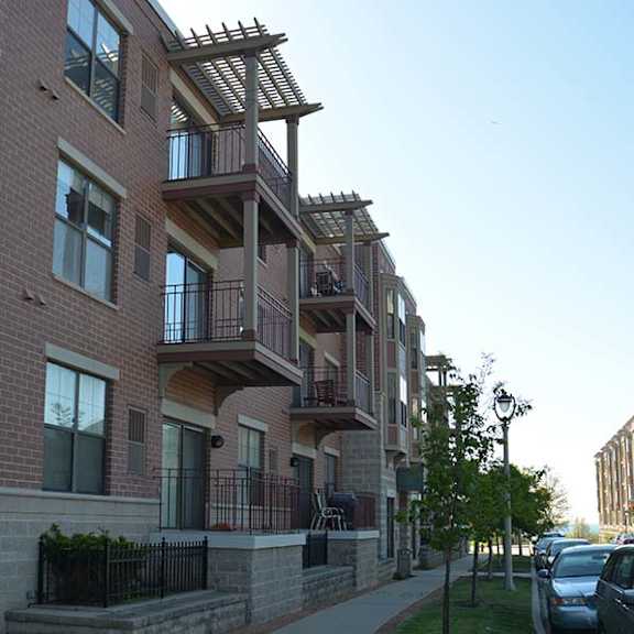 a row of apartment buildings with cars parked in front.