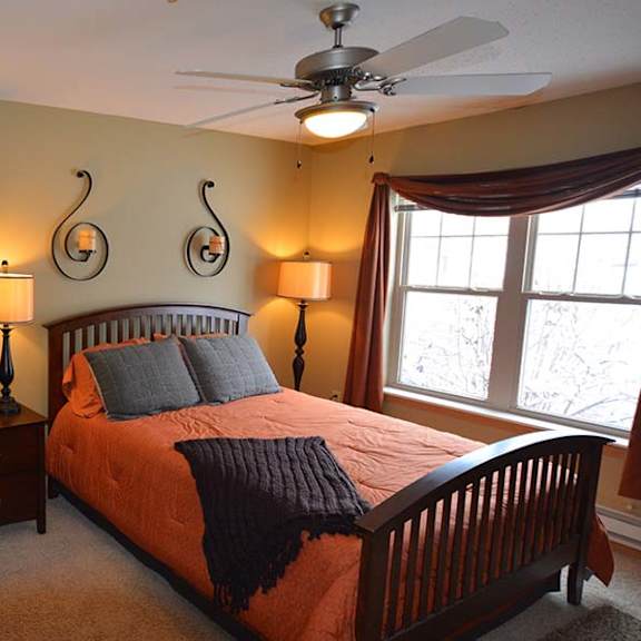 a bedroom with a bed, nightstand, and a ceiling fan.