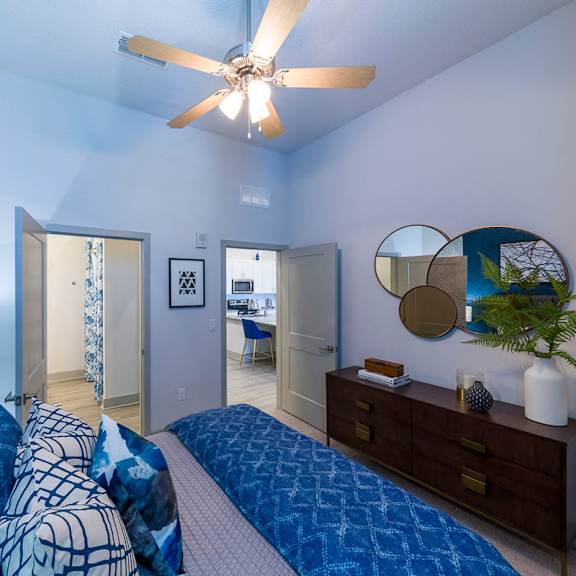 Thumbnail 3 of 9 Modern bedroom with blue bedding and ceiling fan at Ciel Luxury Apartments, Florida, 32246
