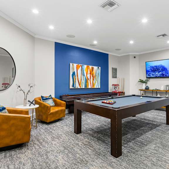 A room with a pool table and a television.