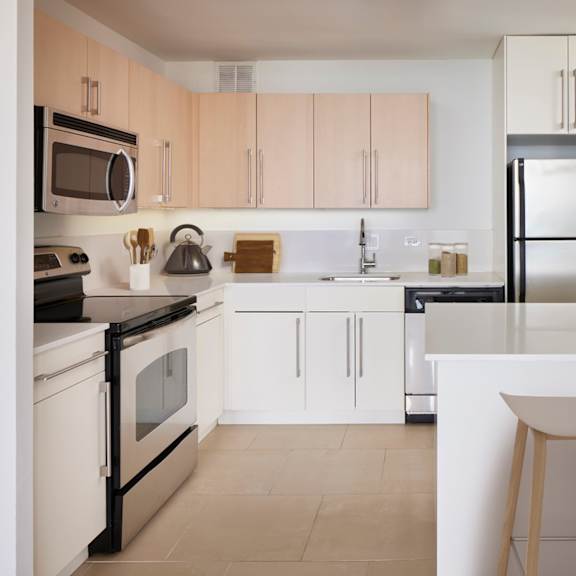 a kitchen with white appliances and wooden bar stools.