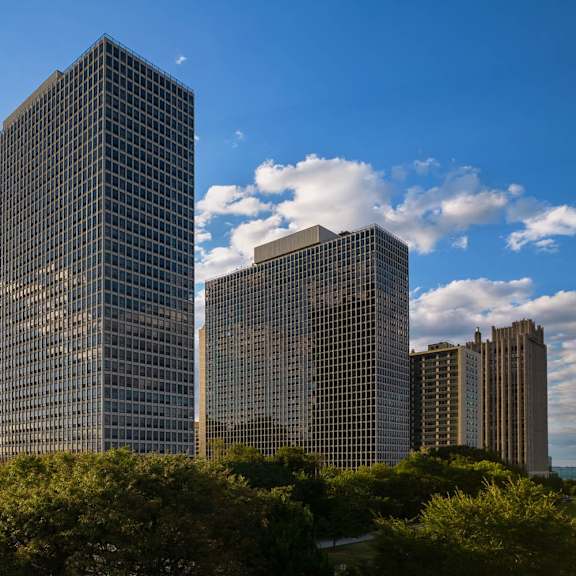 a large glass building stands in front of a skyline.