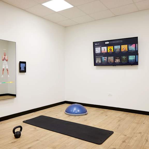 a room with a mirror, a television, a yoga ball, and a kettlebell.