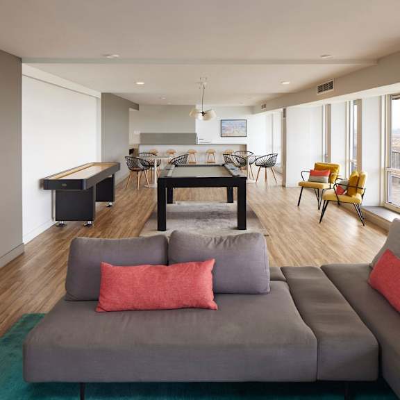 a living room with a grey couch and a green rug.