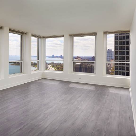 a large empty room with wooden floors and windows overlooking a body of water.