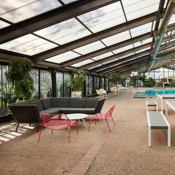 a patio with a table and chairs is covered by a glass roof.