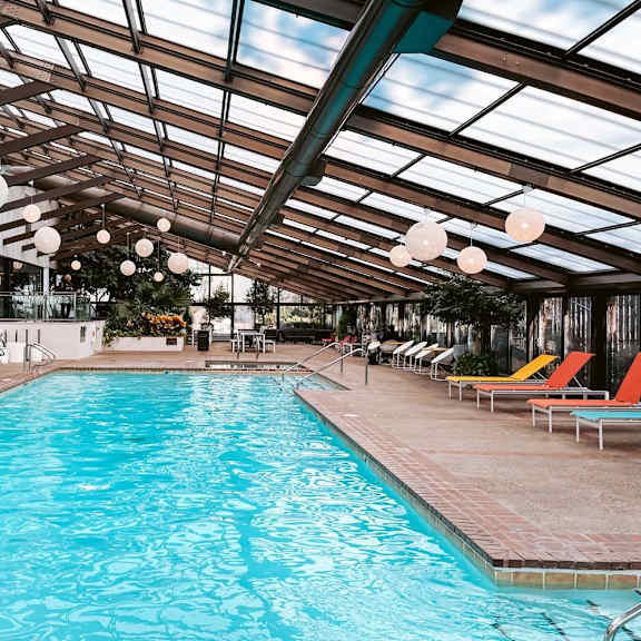 a large indoor swimming pool with sun loungers and a glass ceiling.