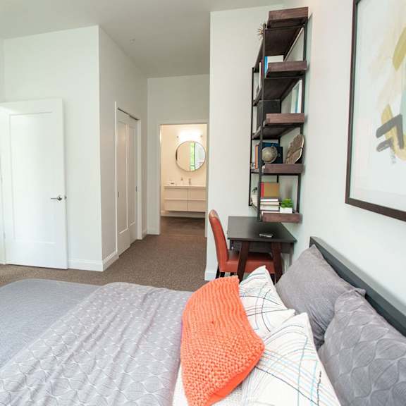 a bedroom with a bed, a chair, a dresser, and a painting on the wall.