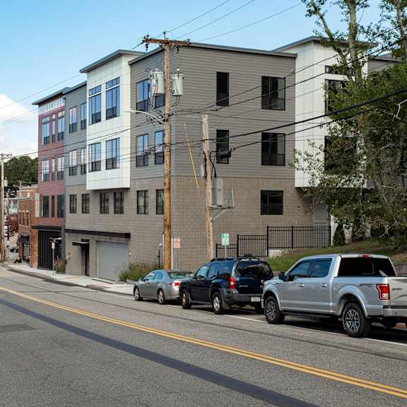 a street with cars parked on the side and buildings in the background.