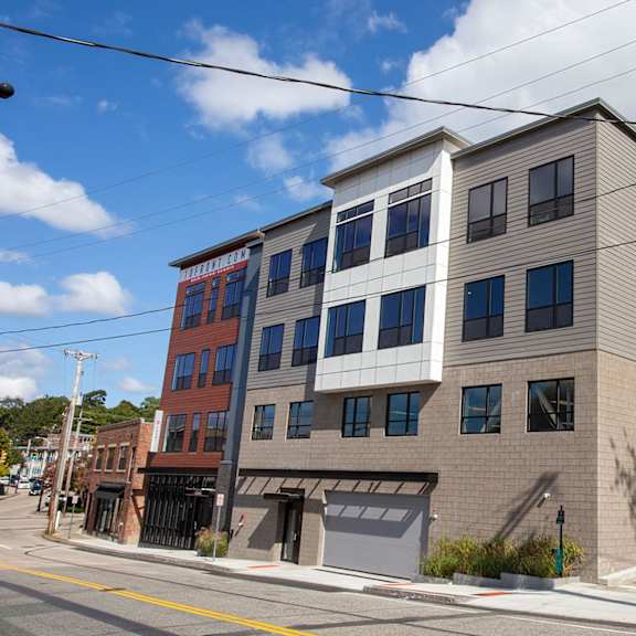 a modern building with a grey facade and a red brick building in the background.