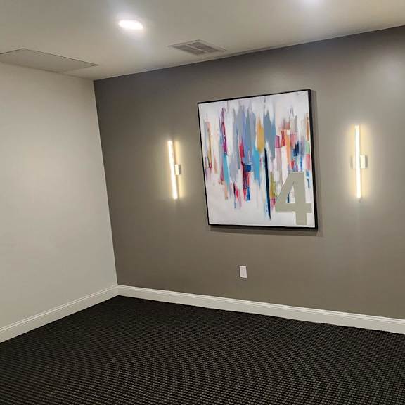 a room with a painting on the wall and two lights on either side of it.