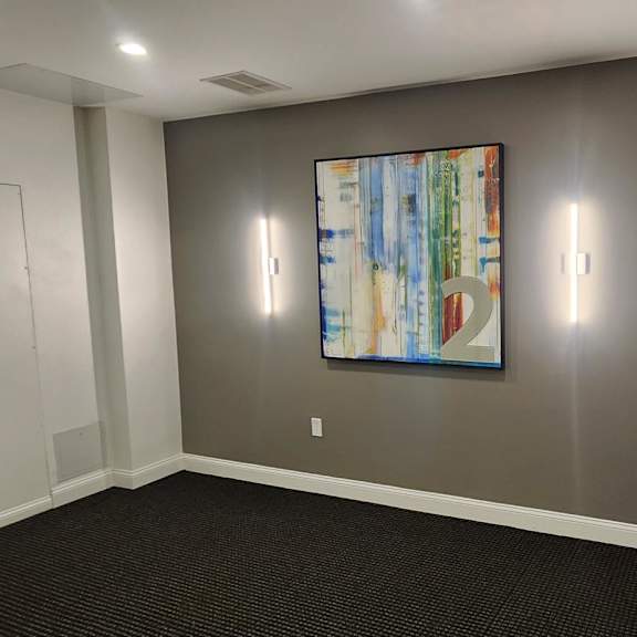 a room with a painting on the wall and a door on the left.