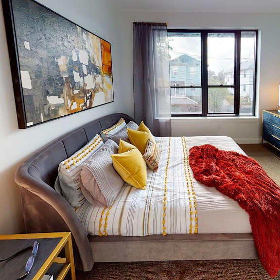 a bedroom with a bed, nightstand, and a painting on the wall.