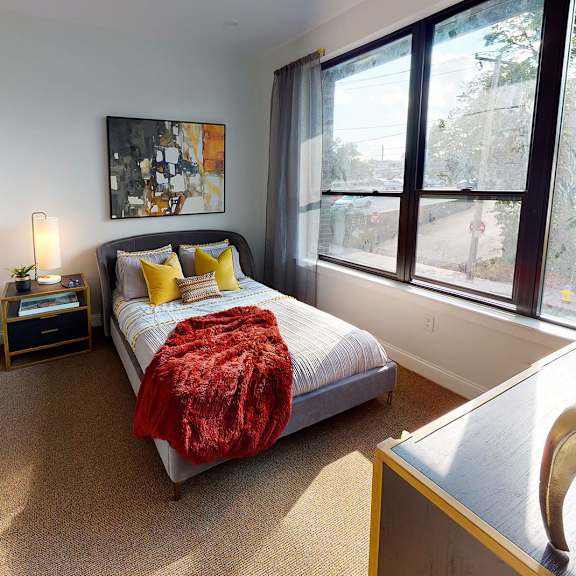 a bedroom with a bed, a nightstand, a chair, and a painting on the wall.