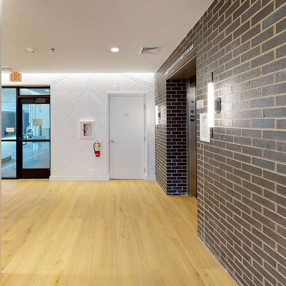 a hallway with a wooden floor and a brick wall on the right side.