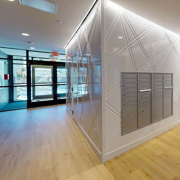 a white hallway with a black railing and a white wall with a geometric design.