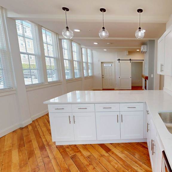 a kitchen with white cabinets and a wooden floor.