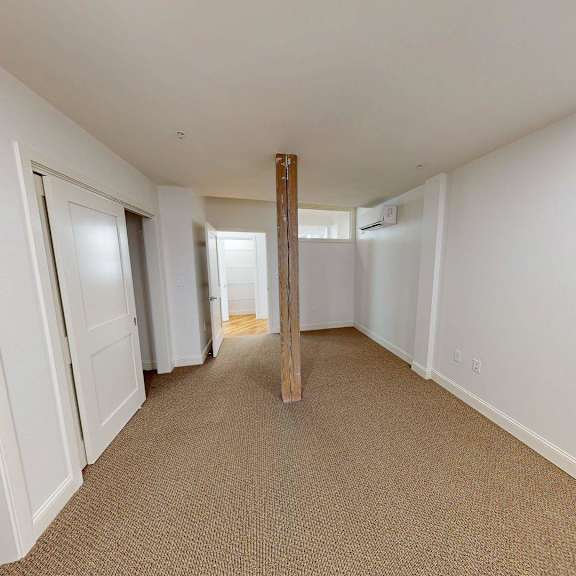 a long hallway with white walls and carpeted floor.