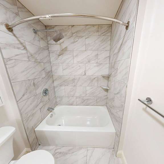 a white bathroom with a tub, toilet, and shower.