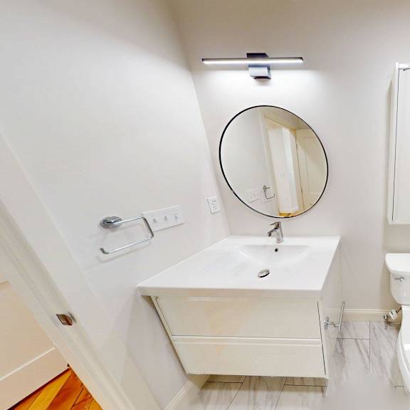 a white bathroom with a marble tile shower.