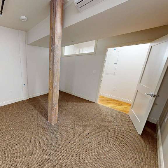 a room with a carpeted floor and a large pillar in the middle.
