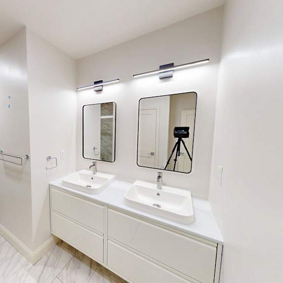 a white bathroom with a toilet, sink, and mirror.