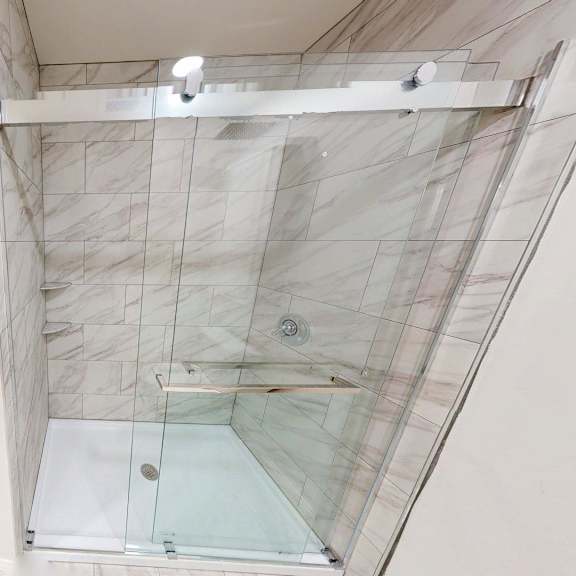 a bathroom with a walk-in shower and a white door.
