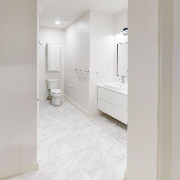 a white bathroom with a toilet, sink, and mirror.