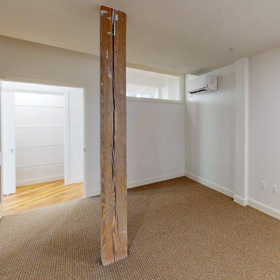 a room with a carpeted floor and a wooden pillar.