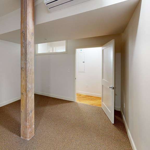 a room with a carpeted floor and a wooden pillar.