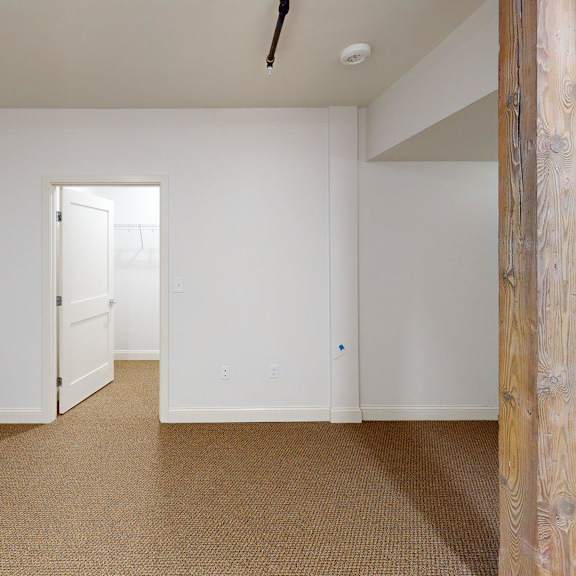 a room with a carpeted floor and a wooden pillar.
