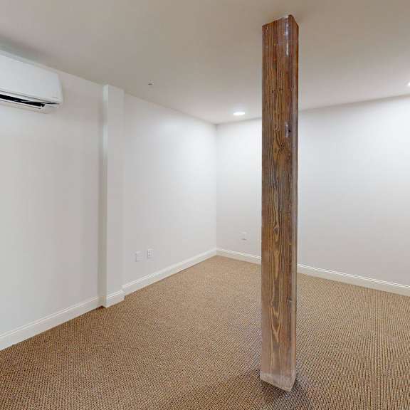 a room with a carpeted floor and a wooden pillar.