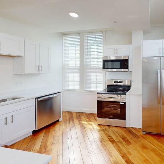 a modern kitchen with wooden floors and stainless steel appliances.