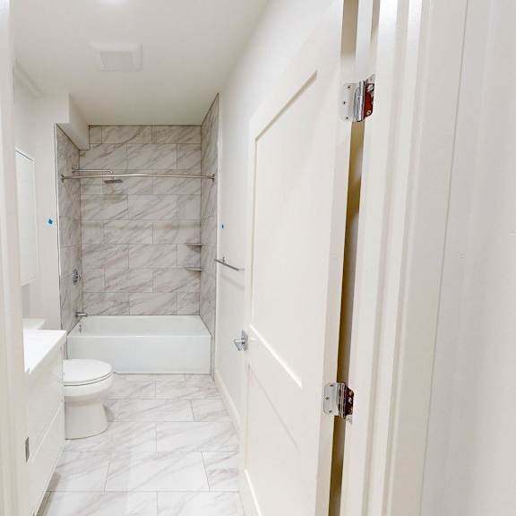 a white bathroom with a marble tiled shower.