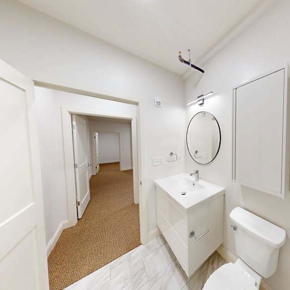 a white bathroom with a toilet, sink, and mirror.