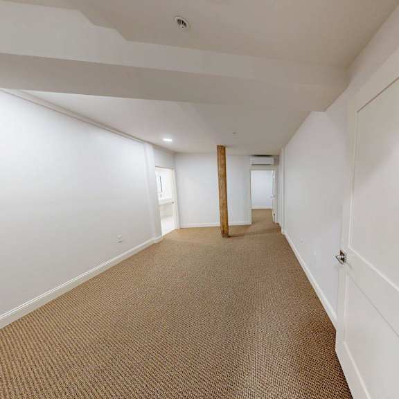 a long hallway with white walls and carpeted floor.