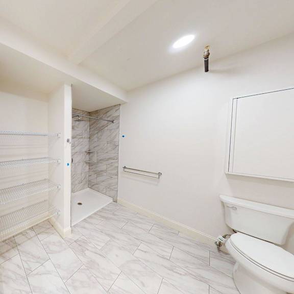 a white bathroom with a toilet, sink, and shower.