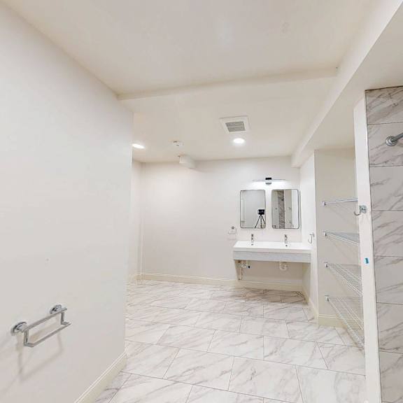 a white bathroom with a marble tile shower.