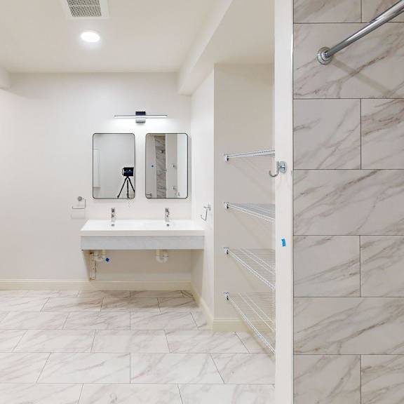 a bathroom with a white sink and marble tiles.