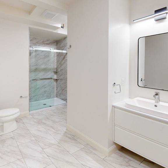 a bathroom with a toilet, sink, and mirror.