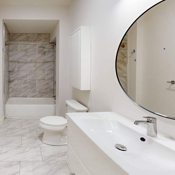 a white bathroom with a marble tile shower.