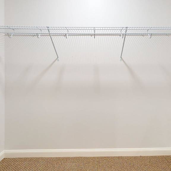 empty white closet with a metal rack.