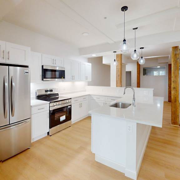 a modern kitchen with wooden floors and stainless steel appliances.
