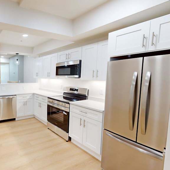 a modern kitchen with wooden floors and stainless steel appliances.