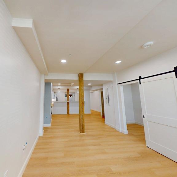 a long hallway with a white wall and a wooden floor.
