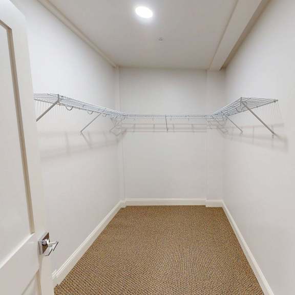 a white closet with a carpeted floor and a single hanger.
