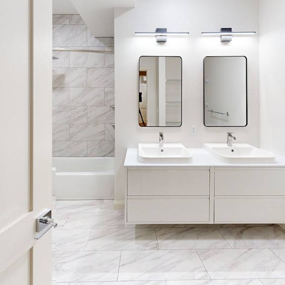 a bathroom with two sinks and a marble wall.