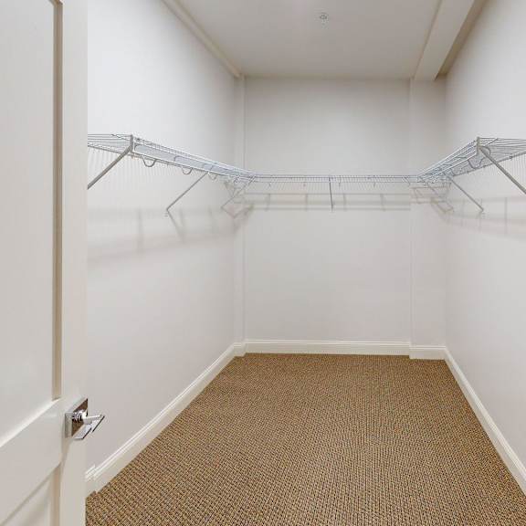 a white hallway with a carpeted floor and a coat rack.