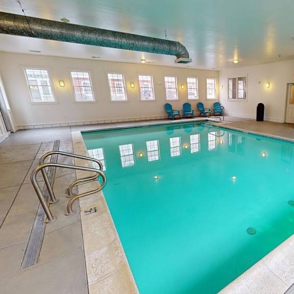a large indoor swimming pool with lounge chairs and a tiled floor.