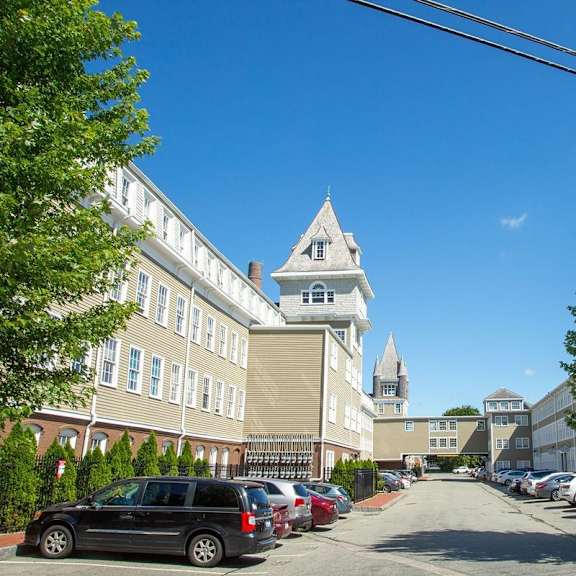a street view of a building with a tower and cars parked on the side.